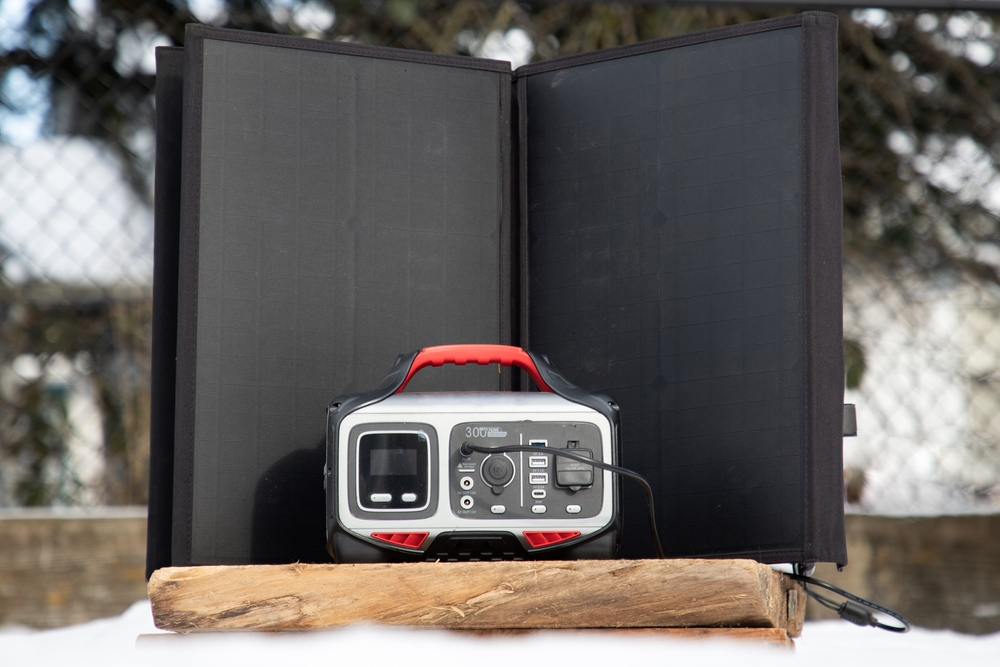 Portable solar battery charging from suitcase style solar panels on a snowy day