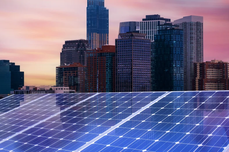 Solar panels over the image of skyscrapers and a sunset