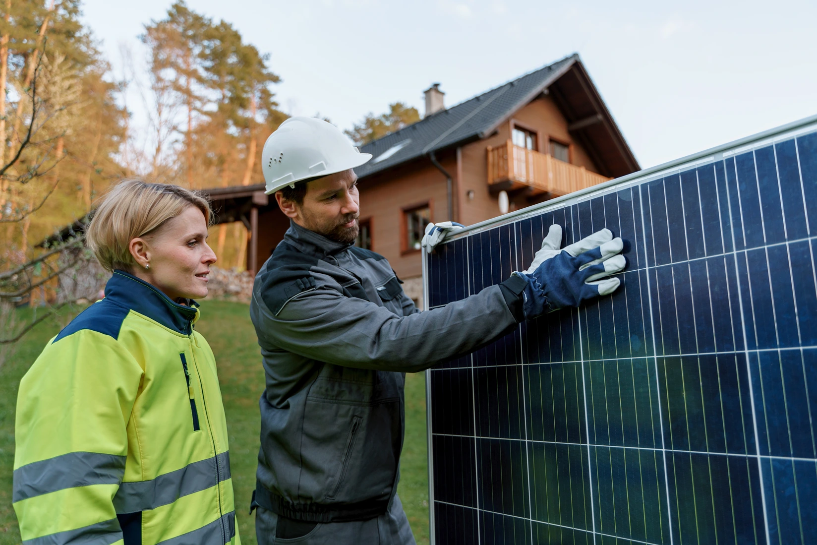 Male and female engineers installing photovoltaic panels on the house for energy independence.