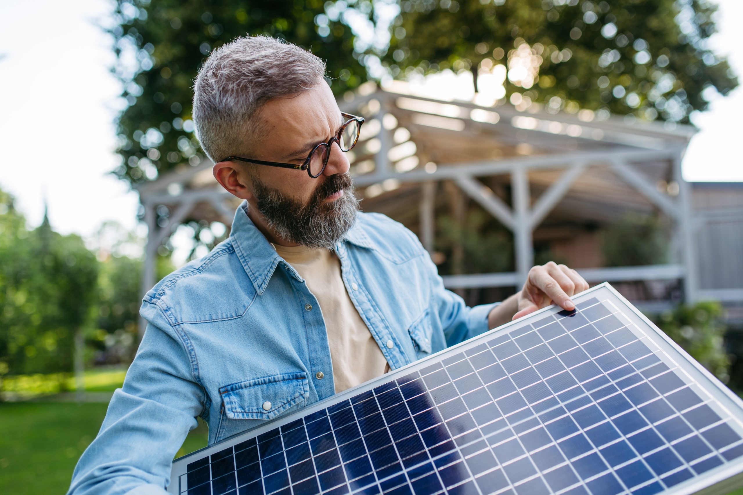 A man looking at a solar panel trying to figure out how many panels he needs for his home without a solar panels calculator