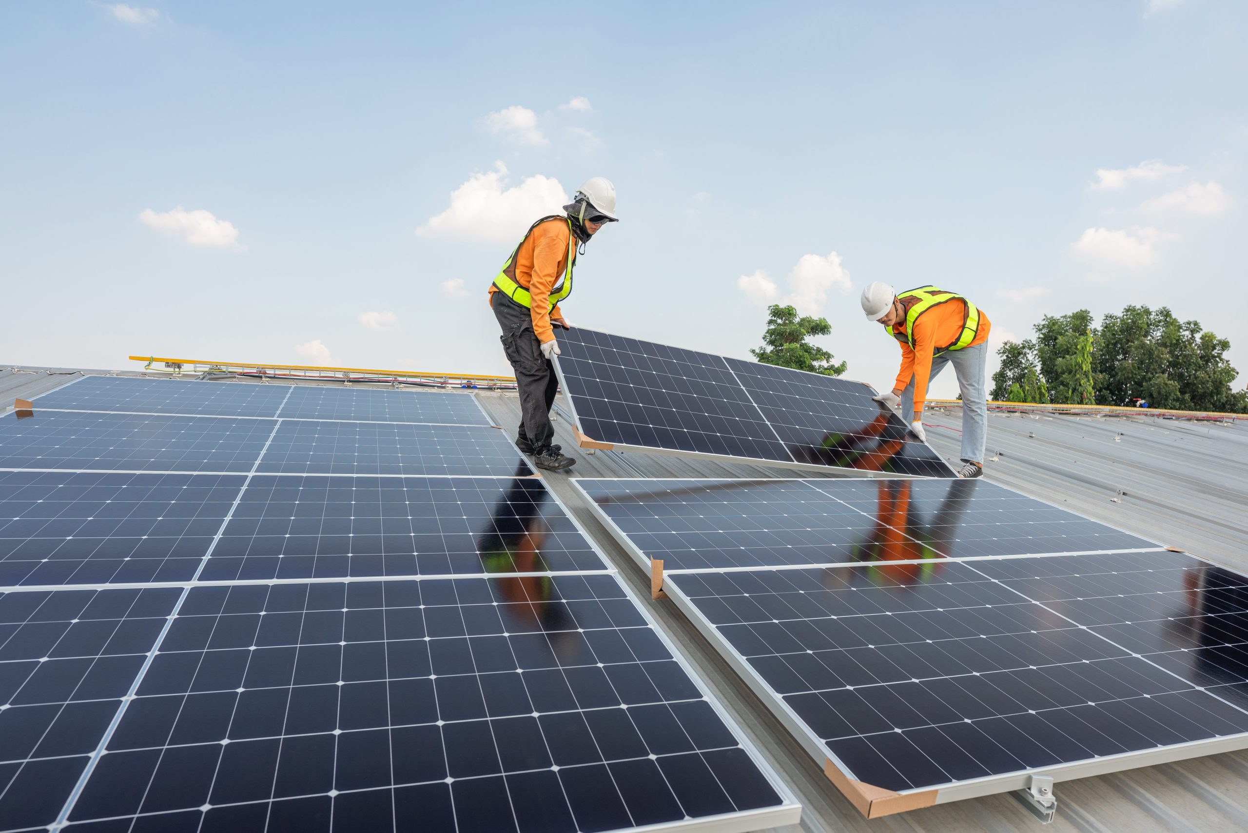 Solar technicians installing solar PV modules on the roof of the building