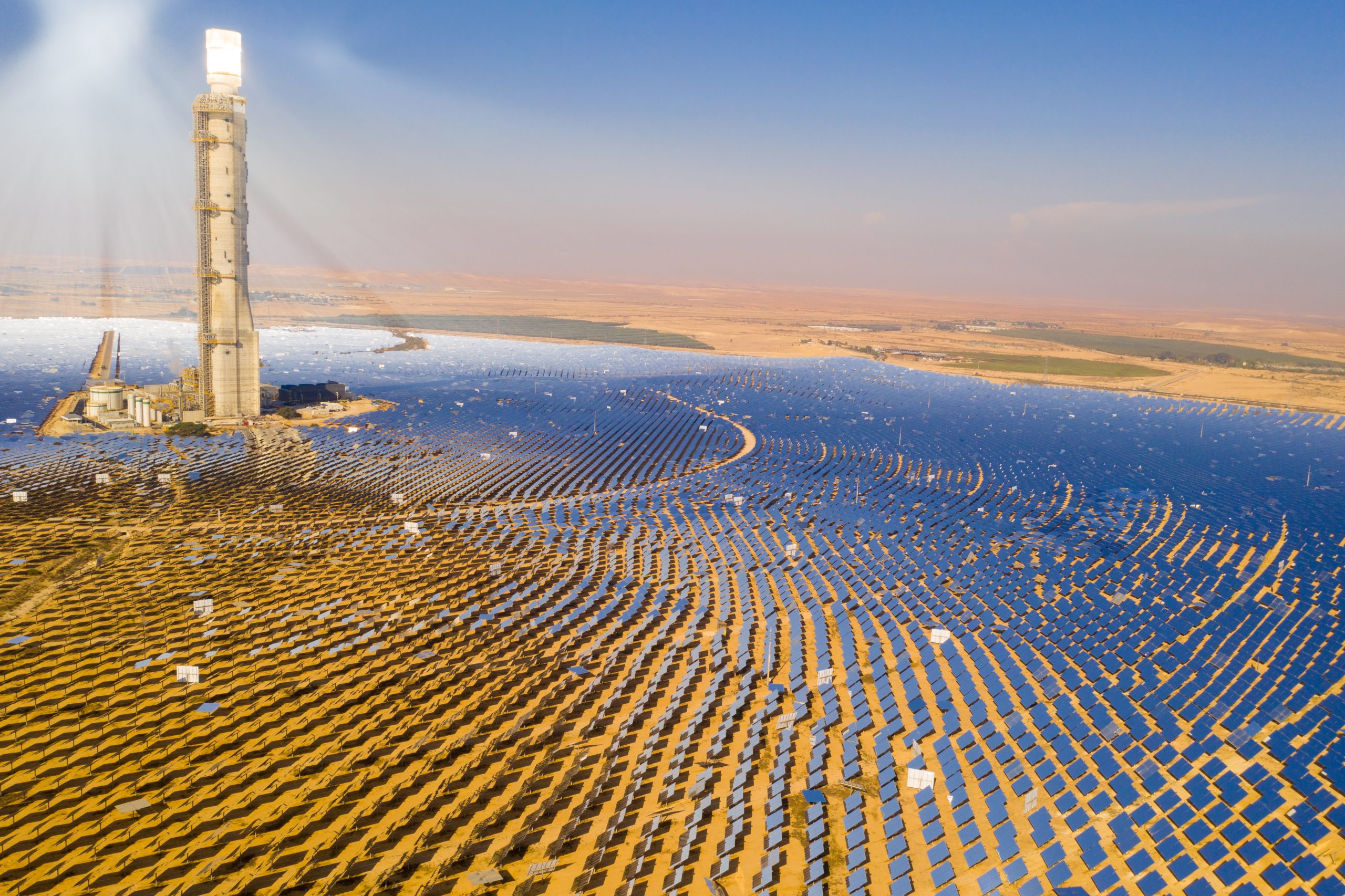 Solar power tower and numerous mirrors around it that direct the sun rays at a tower producing concentrated solar power