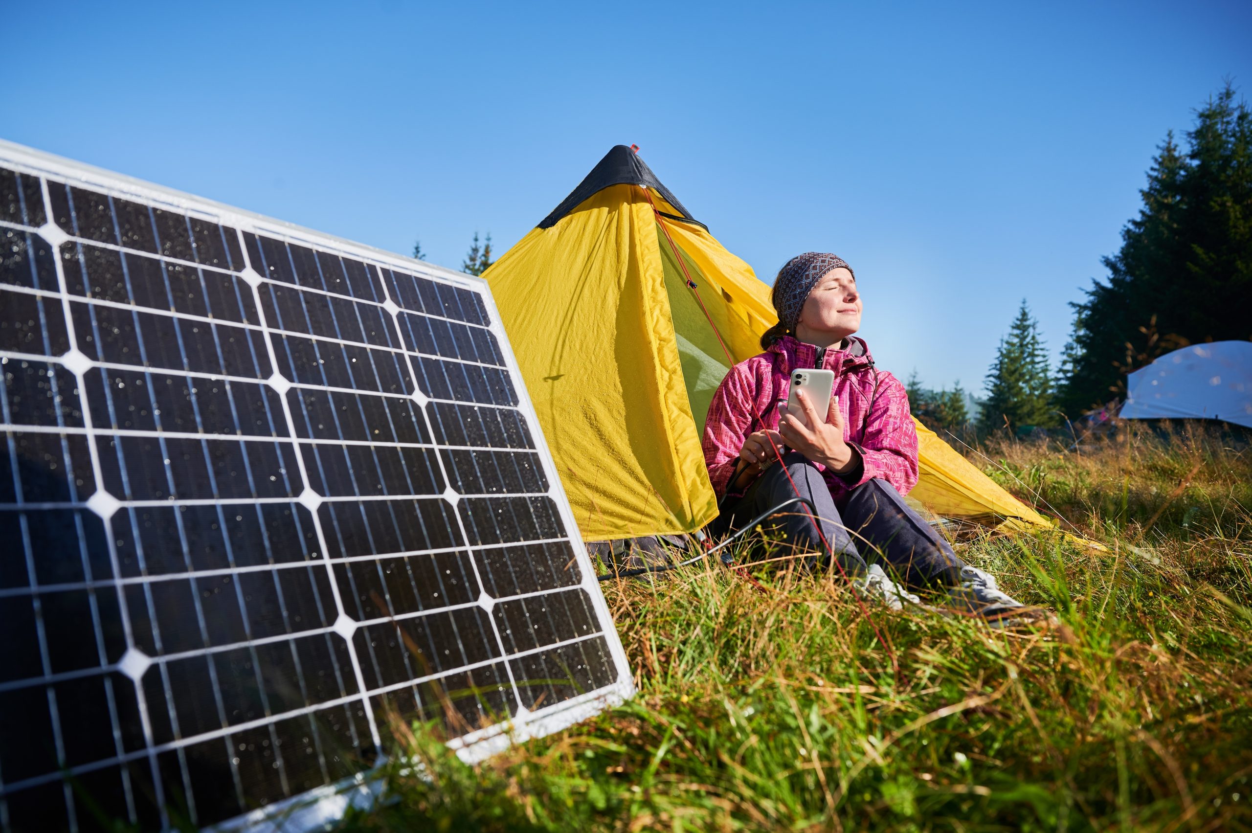 Female tourist hiking and using portable solar power solutions.