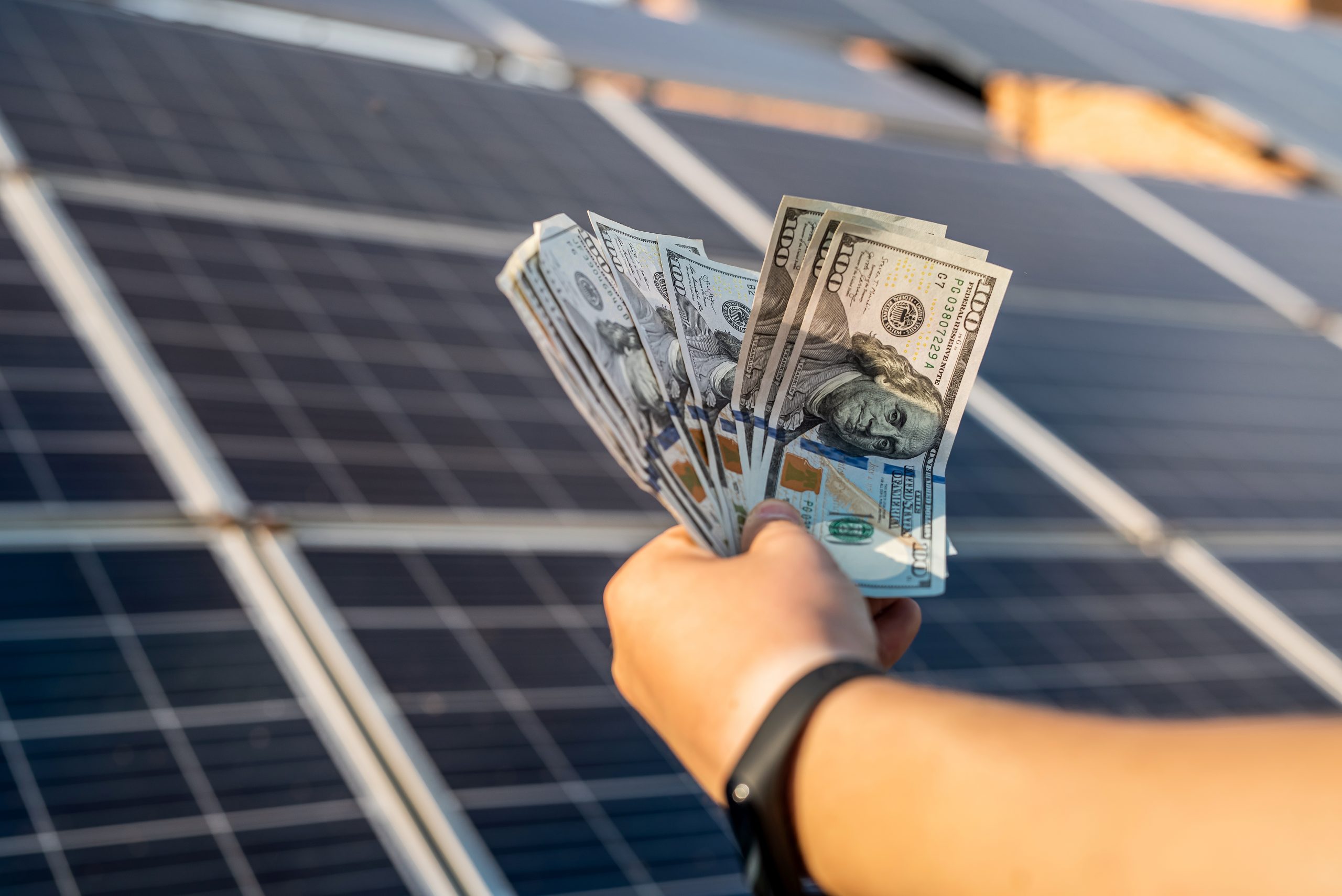 A man holding money in his hand with the DIY solar panels in the background