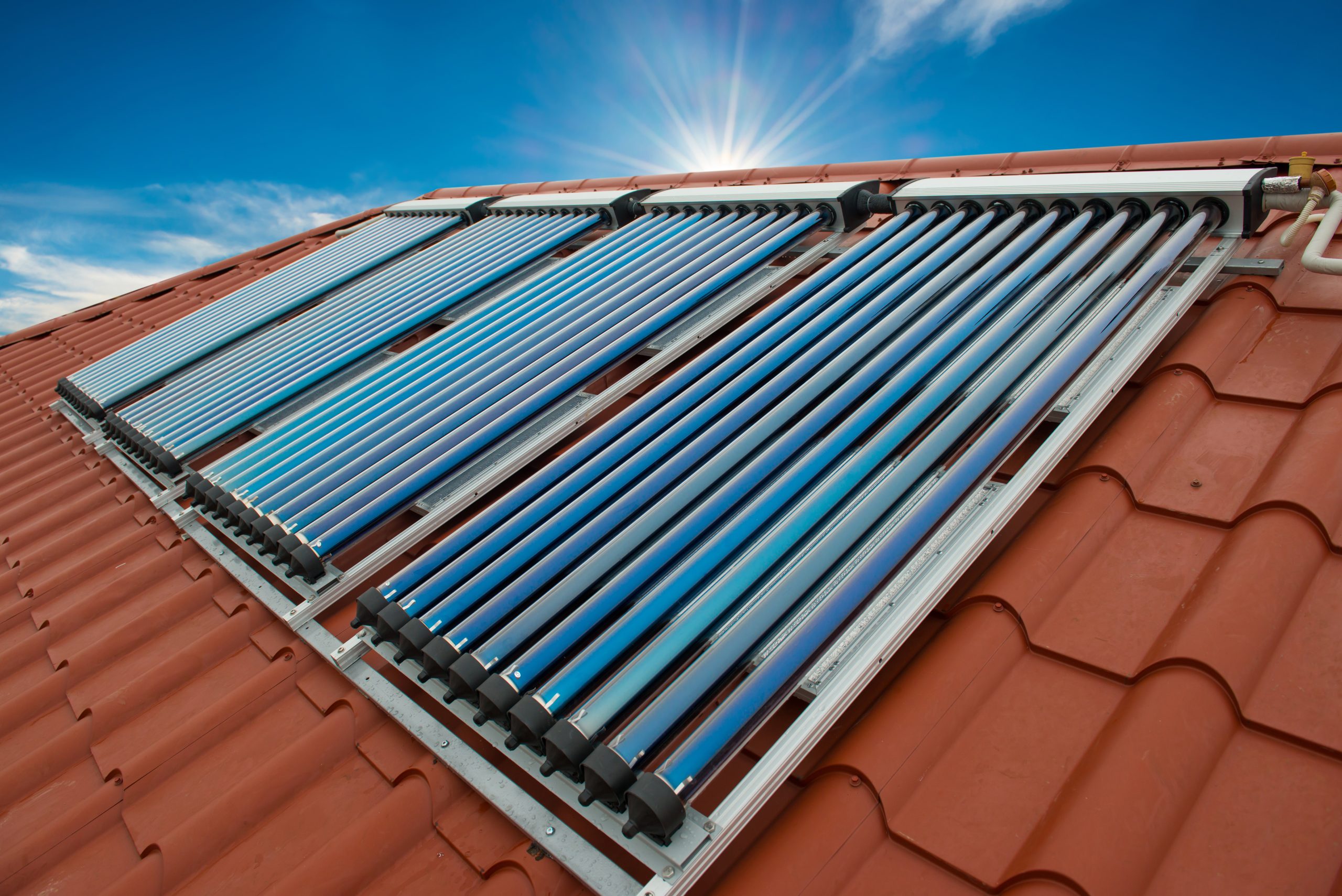 Vacuum collectors: solar water heating system on the red roof of the house.