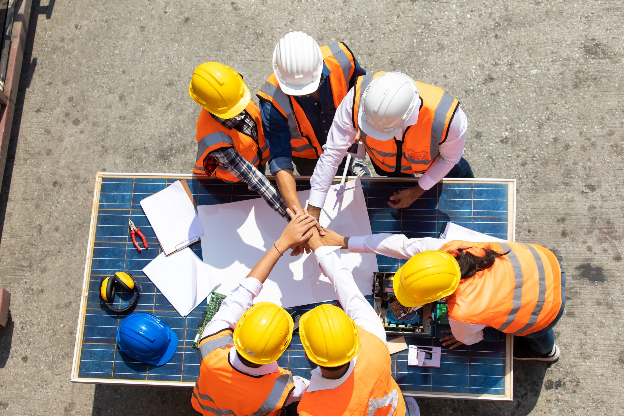 The group of solar panel installers wearing safety helmets discussing the new project