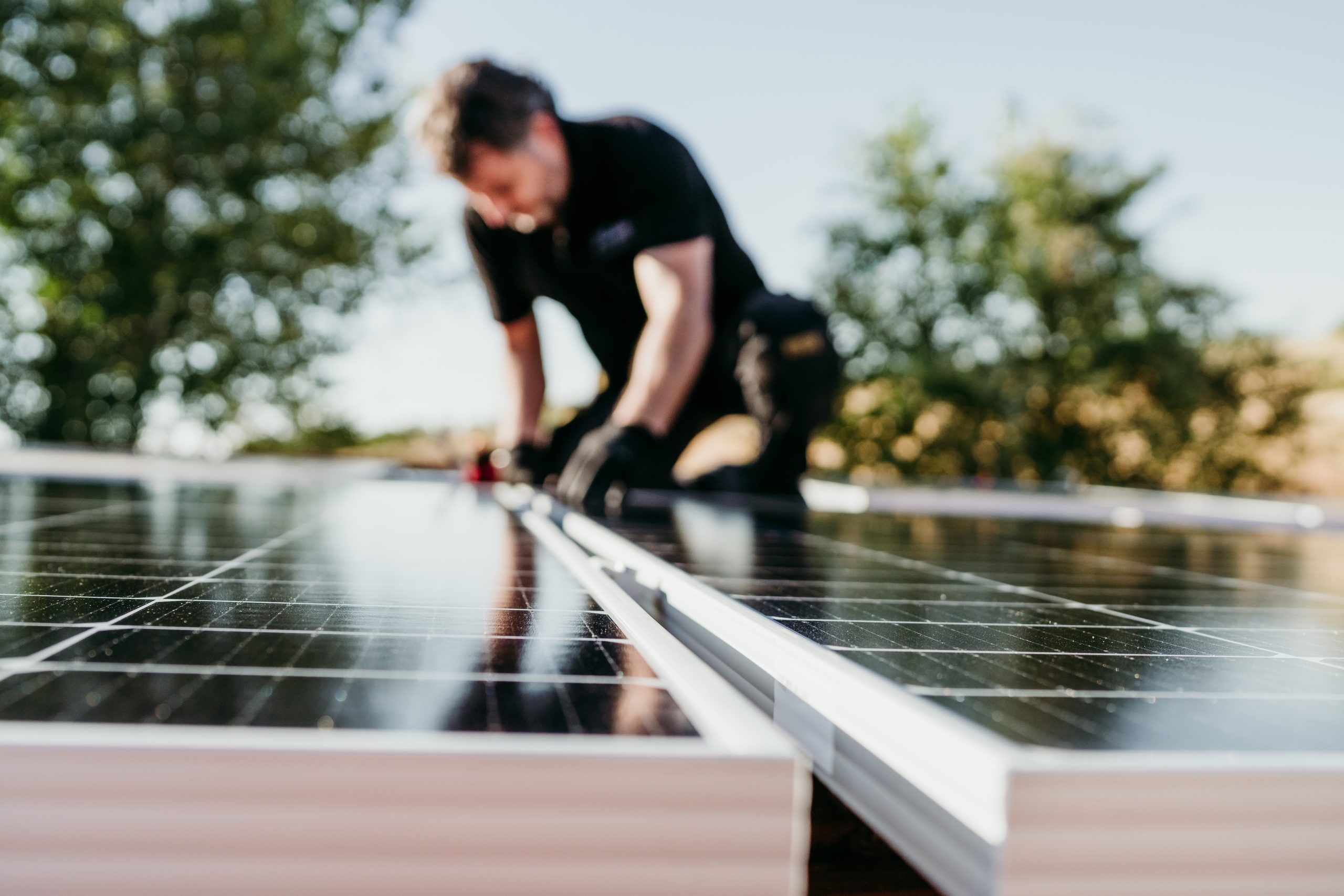 A solar technician assembling solar panels on the roof of the house