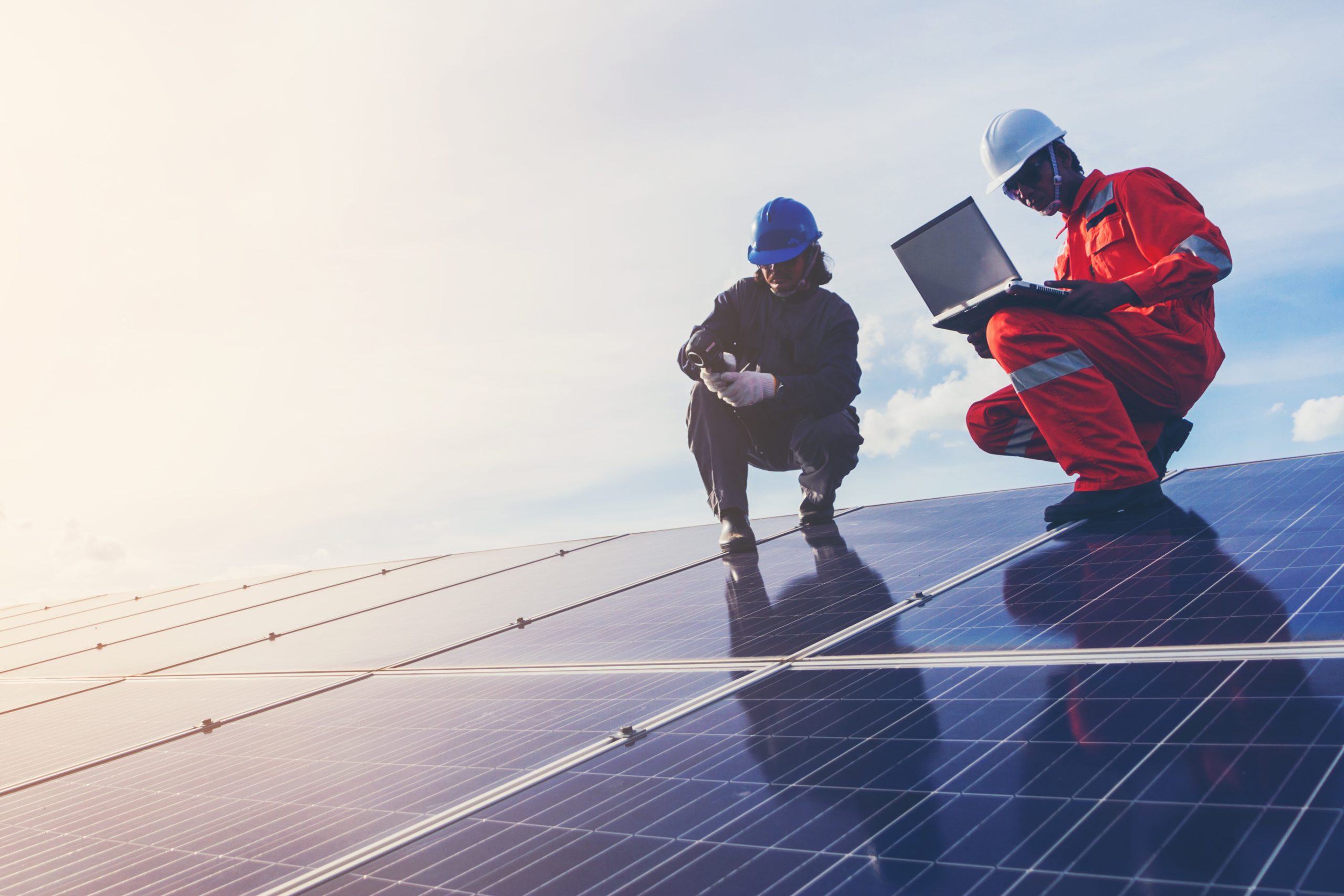 Two engineers on the roof of the building checking the solar equipment with the help of solar software tools