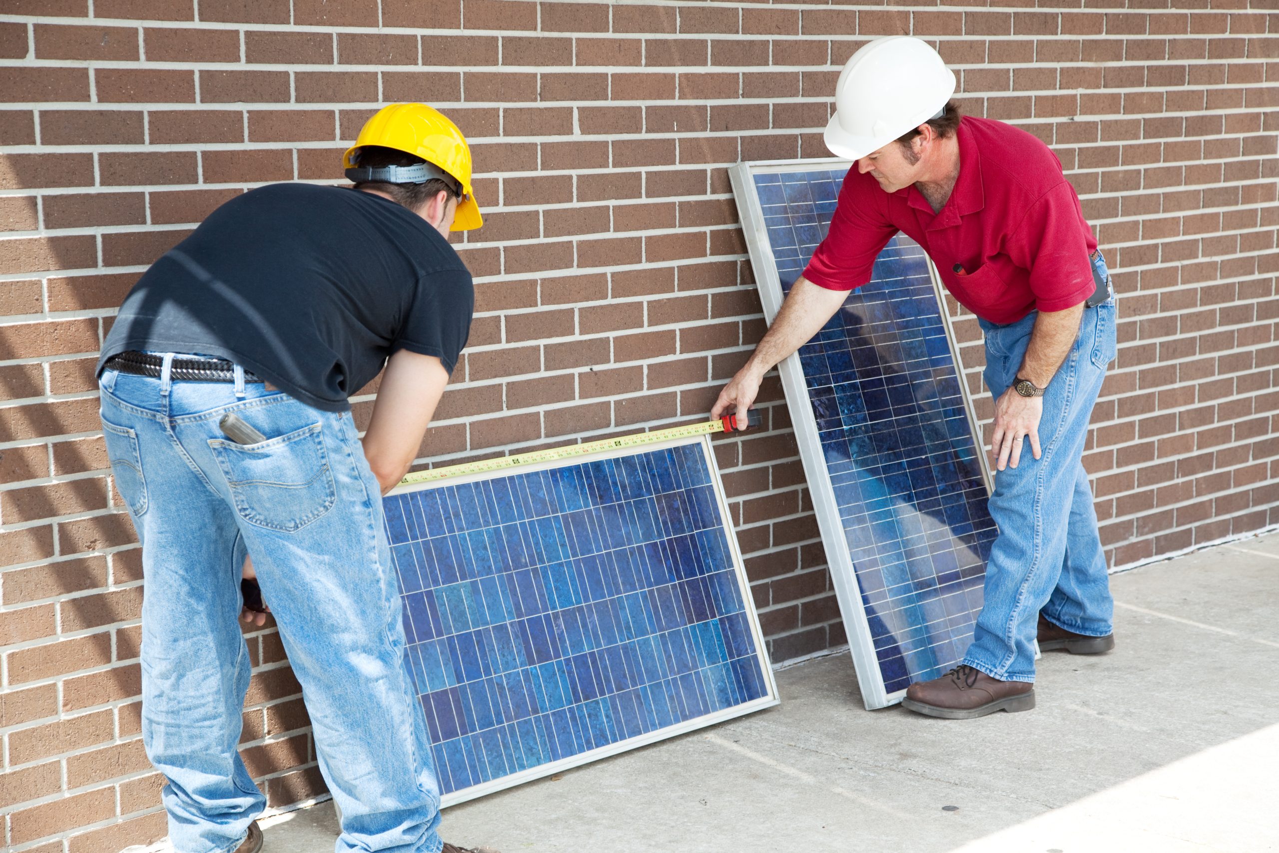 Two workers taking solar panel dimensions prior to installing them