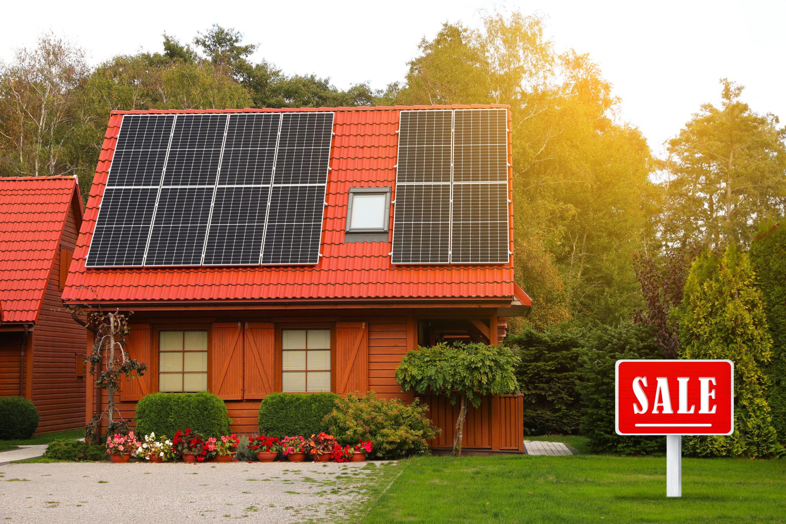 A wooden house with a red roof and the sale sign outside, informing that the owners are selling a home with solar panels