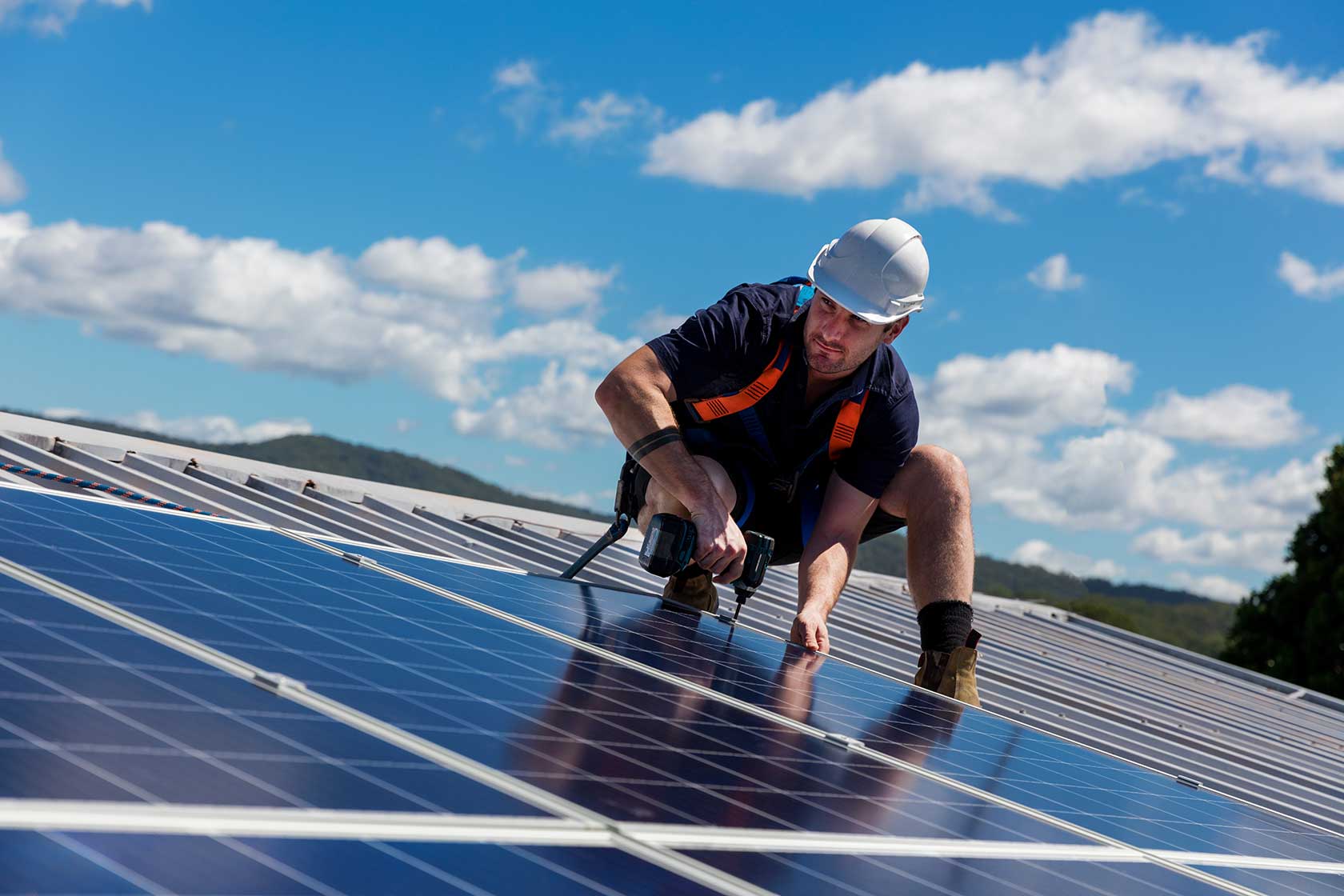 Solar technician working on a rooftop solar array, installing and securing solar panels as part of a hands-on solar installation job.