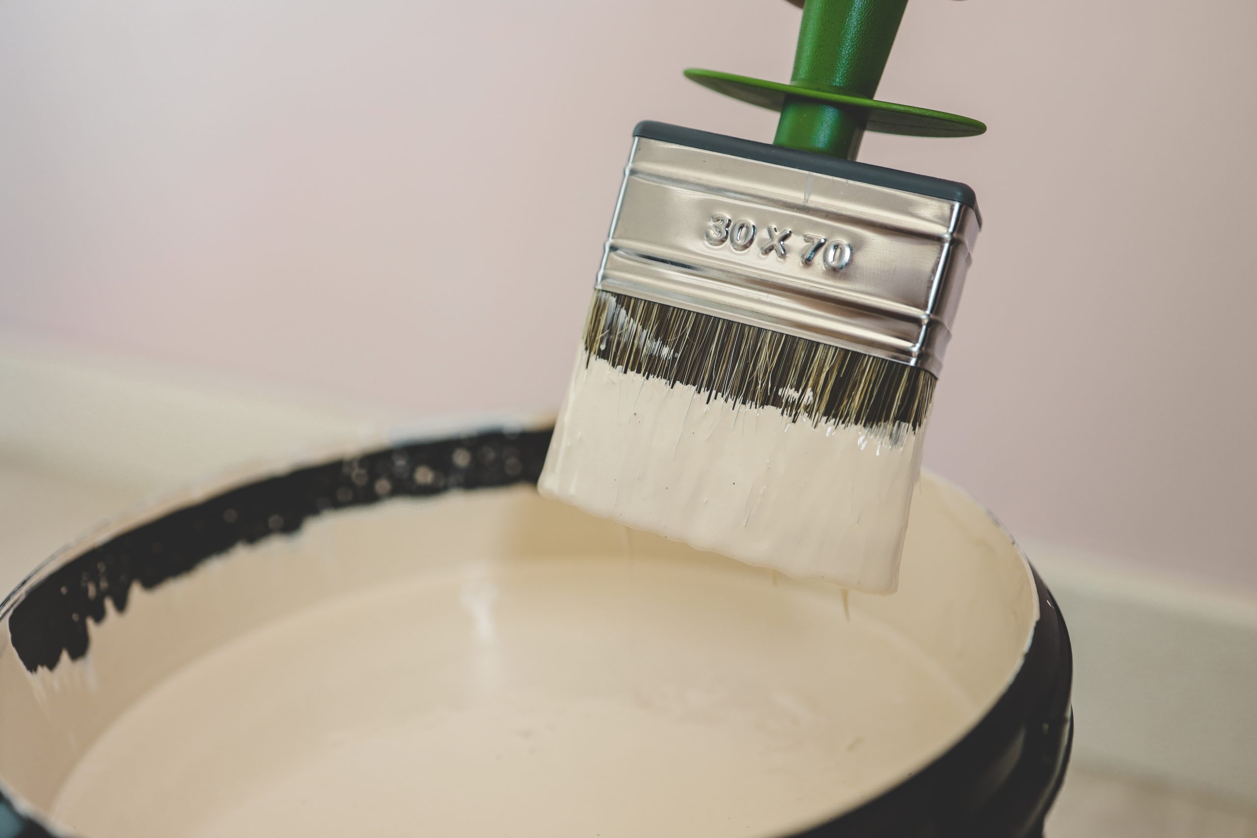 Paintbrush dipped into a bucket of eggshell paint, illustrating the concept of solar paint.