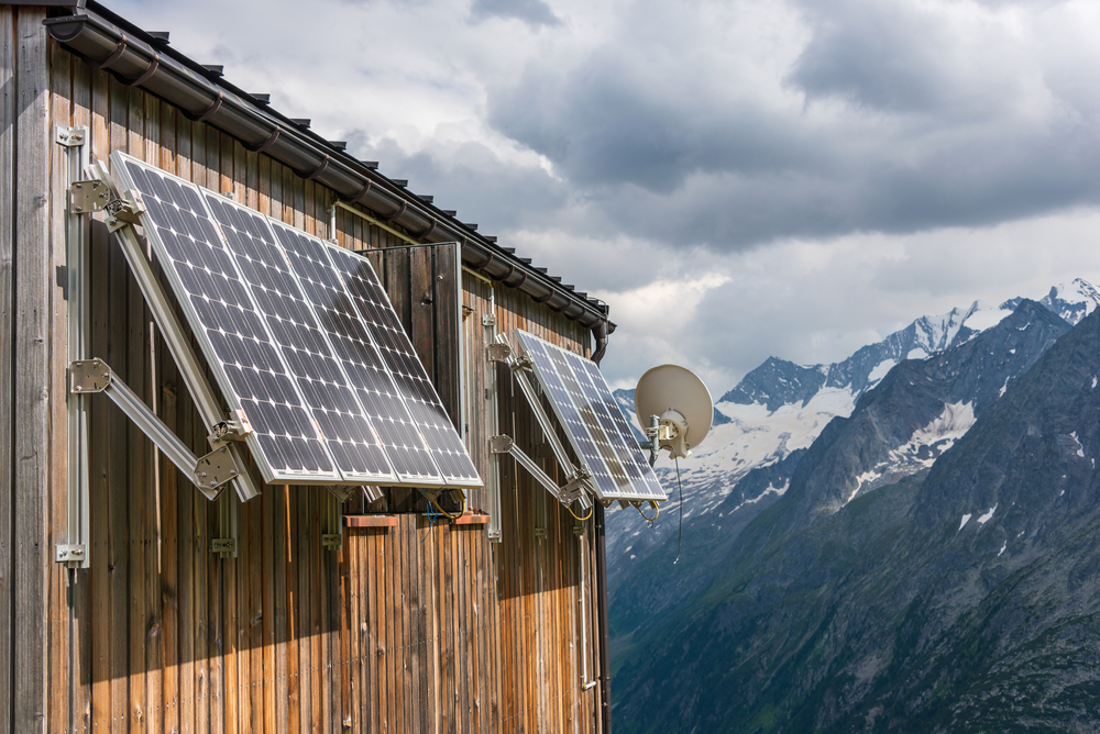 A photo of a high-mountain building with two wall-mounted solar panels.